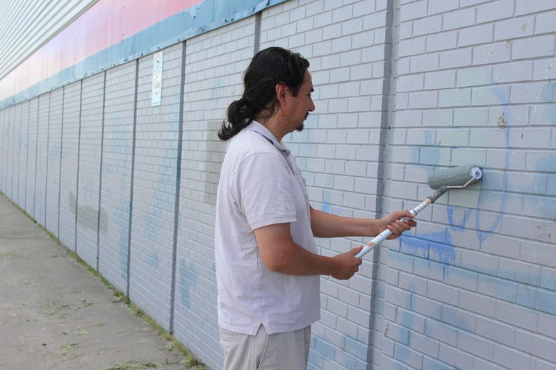 Darren Bighetty paints over some graffiti on the side of the Walmart next to City Centre Mall.