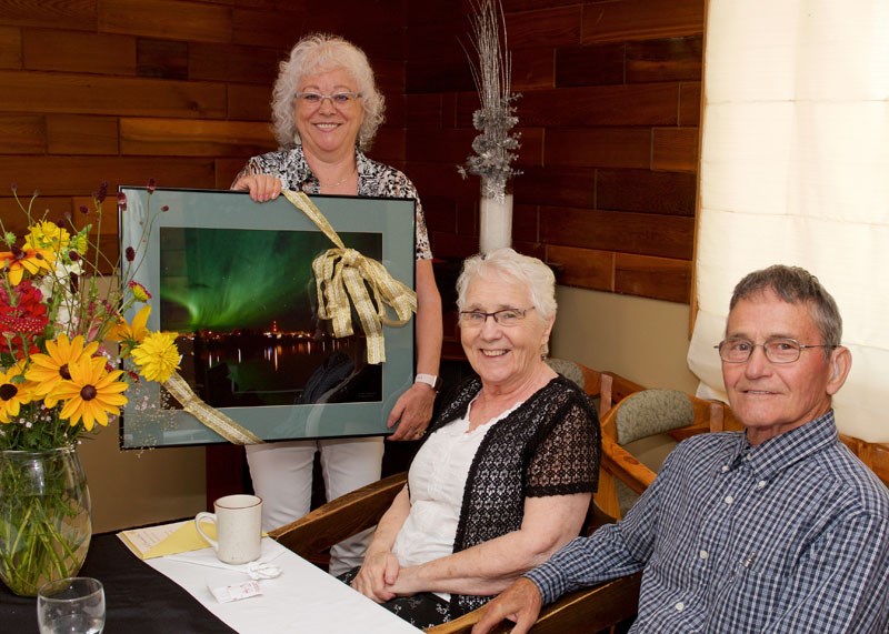 Sylvia Zamzow presenting Betty and Chester Rudd with a going-away photo of the northern lights over