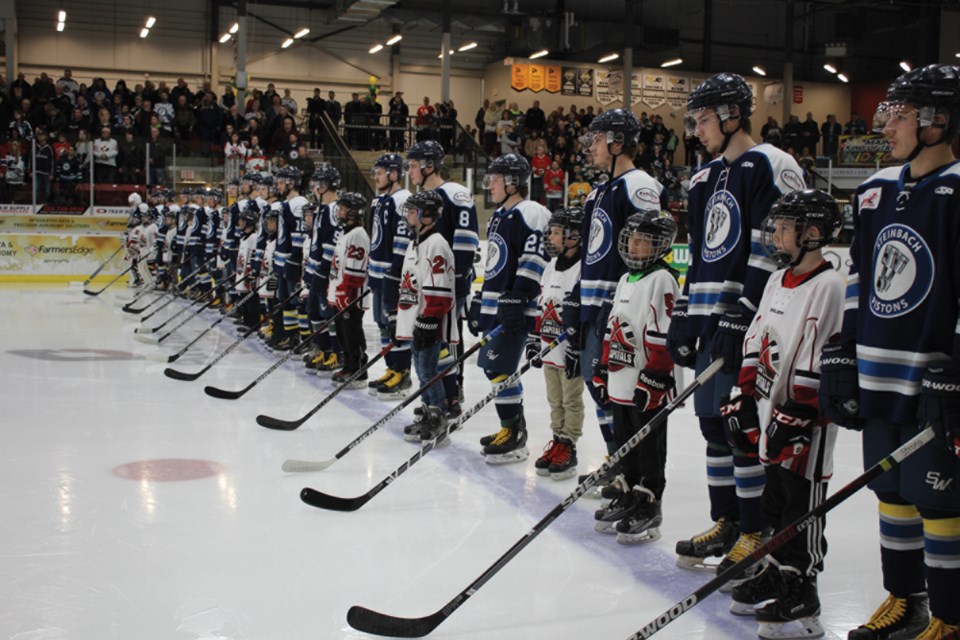 The Steinbach Pistons lined up with Virden minor hockey players, sticks out for the Broncos.