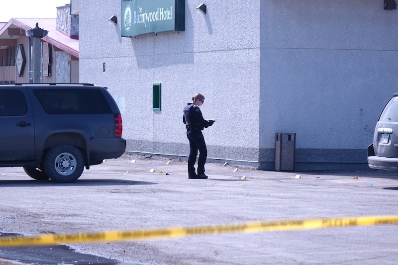 An RCMP officer examines evidence markers in the parking lot of the Burntwood Hotel. An injured man