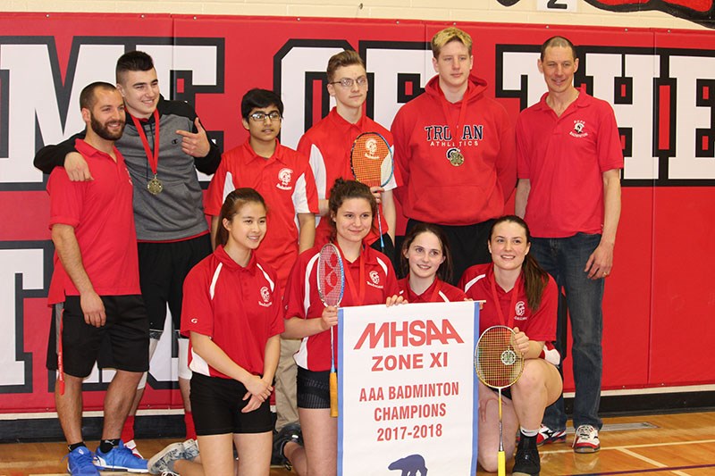 The R.D. Parker Collegiate badminton team celebrates winning the AAA banner at the Zone 11 champions
