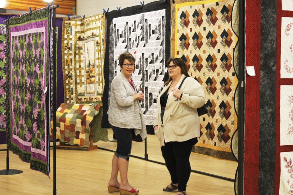 Surrounded with beauty, two visitors admire the handiwork at the Crazy Stitchers Quilt Show in Virden last Saturday.