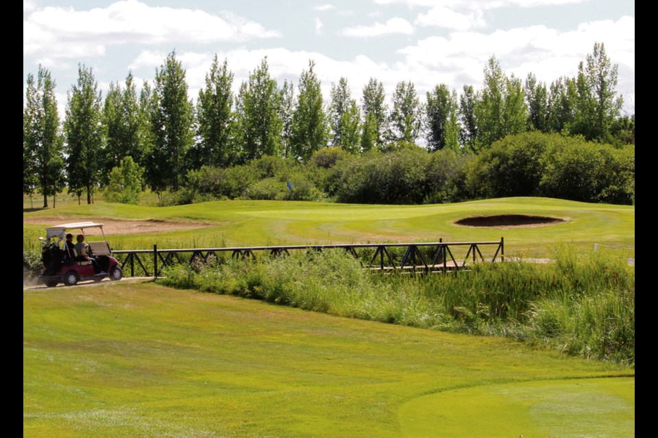 Aug. 1 and couple of afternoon golfers are crossing the bridge over the creek, driving to the seventh green where just last week a certain Virden golfer shot a hole-in-one. Clearly visible is the sand trap to the right and the pin is up to the left.