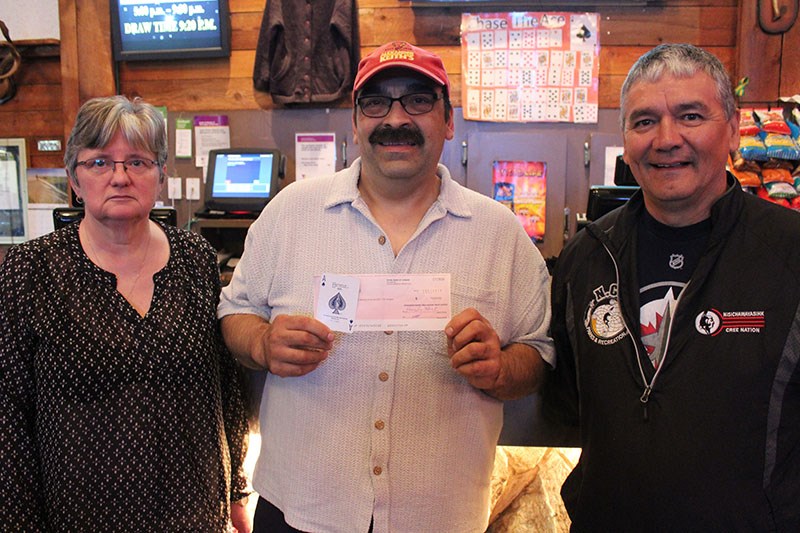 Ward Nevistiuk (centre) accepts his Chase the Ace prize money from Mystery Lake Hotel assistant gene