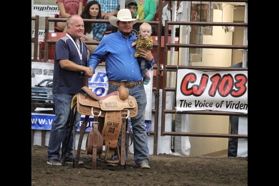Ory Brown, his son in his arms, is awarded 2018 Virden Indoor Rodeo Hi Point Saddle, David Wowk GM of Valleyview Co-op presenting the beautiful saddle, following the sunday evening Shootout Championship, August 19.