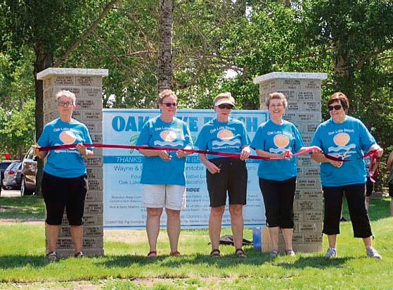 Mid-July, the fundraising committee cuts the ribbon on the donors sign for the playground at Oak Lake Beach.