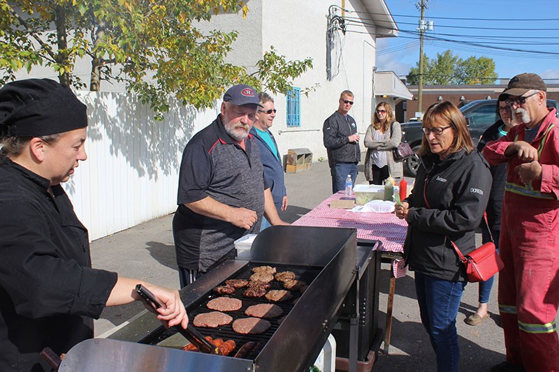 Earl Colbourne, centre, and Mary Lee Spiess, left, serve up hotdogs and hamburgers outside the North