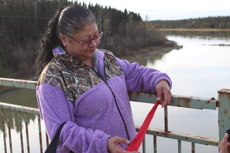 Thompson resident Fran Gibbs ties a red ribbon to the Miles Hart Bridge on Oct. 5 to remember her niece Louise Baker, who was murdered over five years ago.