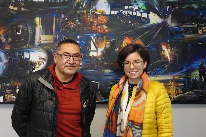 NDP MPs Romeo Saganash and Niki Ashton pose in front of a mural inside the United Steelworkers Local