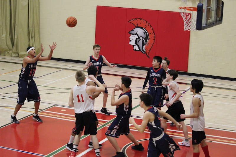 Jacob Fortin (far left) scores in the opening minutes of his team’s Feb. 16 match-up against the Hapnot Collegiate Institute Kopper Kings. The Trojans would go on to win this tournament final by a score of 72−62.