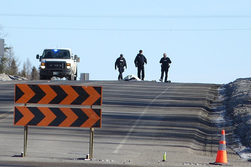 RCMP officers on Highway 391, which has been blocked just north of the Miles Hart Bridge, since some