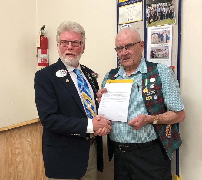 District Governor Gareth Boys (l) presents Lion Clare Couling with a 25-year membership award.