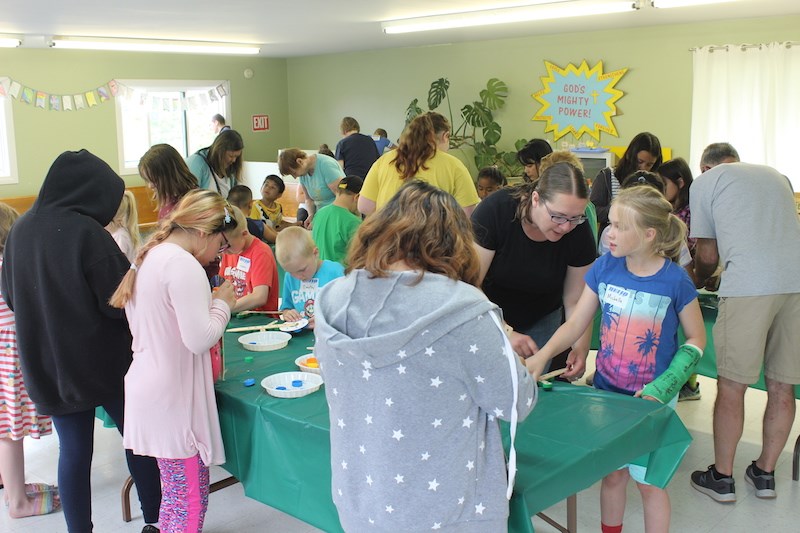 Members of the Lutheran Association of Missionaries and Pilots help local children with their arts and crafts during Bible school July 8 at St. James the Apostle Anglican Church.
