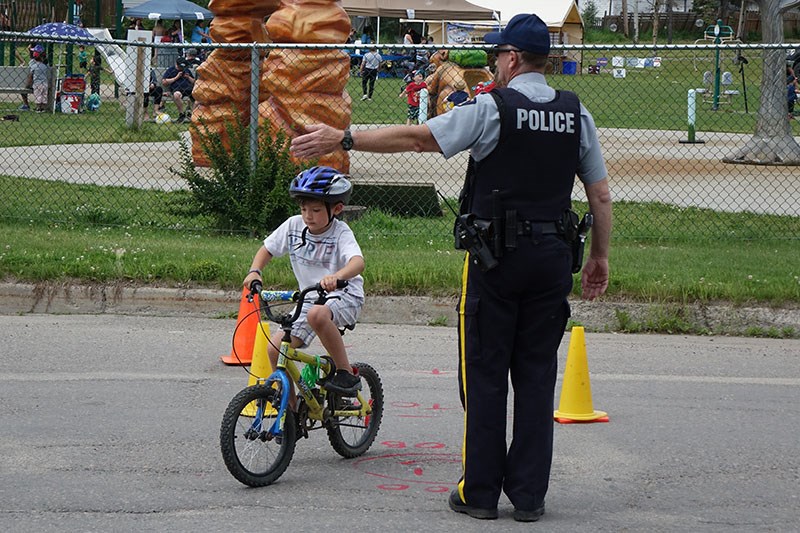 Terrence Mossip, 6, gets instruction from Thompson RCMP Special Const. Rob Cleveland on safe biking practices during the Hello Parents Network of Thompson Safe Kids Day celebrations July 18 at the Rotary Park Splash Pad.