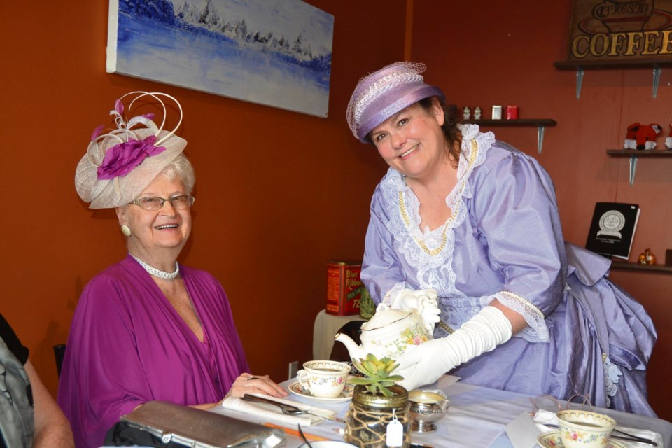 Long gowns, big hats and fascinators were the order of the day. Evelyn Wright (l) accepts tea from Deanna Doucette, who organized the tea as a fundraiser for the Virden Pioneer Home Museum.
