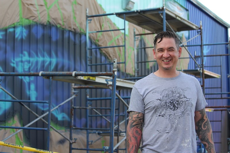 Jasyn Lucas takes a break from working on his latest outdoor mural July 30 at the Boreal Discovery Centre.