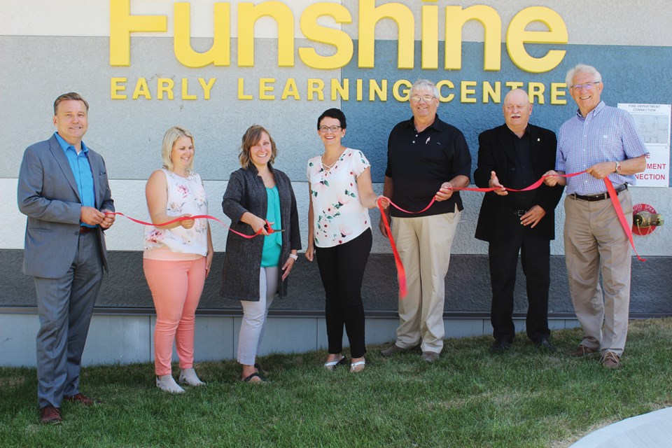Members of the Virden community look on as Director of Funshine II Melony Frank snips the ribbon to celebrate the Grand Opening of Funshine Early Learning Centre, July 26. Holding the ribbon, (l-r) MLA Doyle Piwniuk, Co-Chair of the Funshine board and expansion project Jillian Irvine and Shelby Rampton (former co-chair), Chair of Fort La Bosse School Board Garry Draper, Mayor of Virden Murray Wright and MP Larry Maguire.