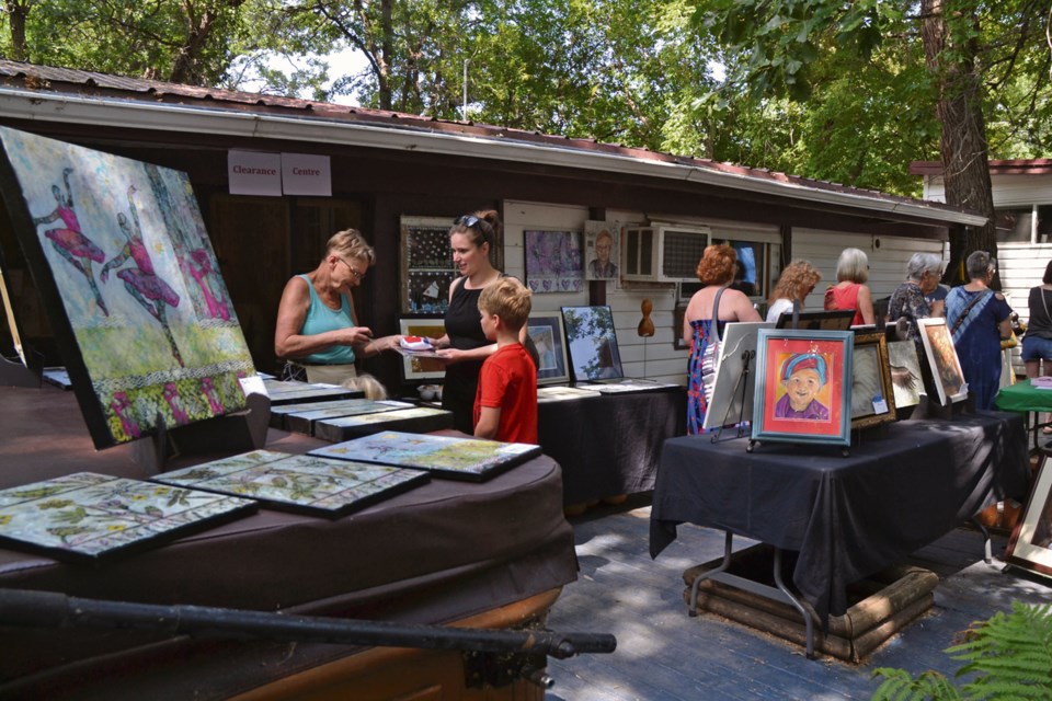 Art Walk co-organizer Bev Karnes rings up a sale in her bustling backyard.