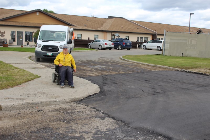 Thompson resident Kristopher Blake poses next to the pothole in front of Harmony House that was finally filled Sept. 13 after five years.
