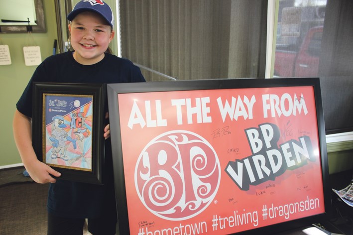 Becca Collier with the framed colouring contest page and the sign she took from Virden, autographed at the Jays game.