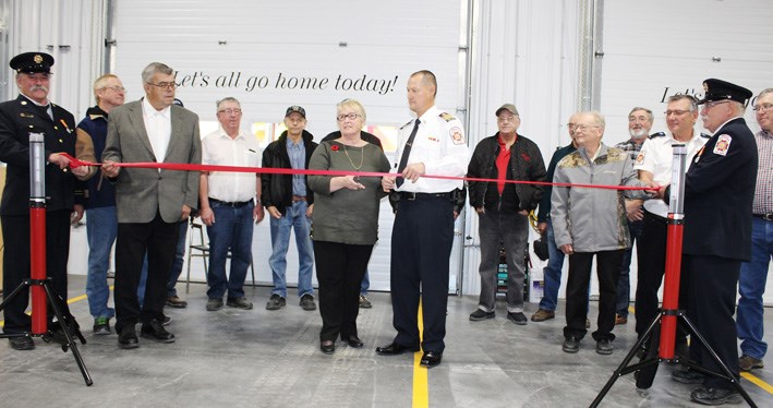 Cutting the ribbon - Prairie View Reeve Linda Clark and Fire Chief Nick Young. Participating: Miniota firefighters past and present include uniformed Captain Darcy Oliver (l) and Deputy Chief Brian Oliver (r); Bruce Mitchell, Ken Armitage, Grant Brown, Bob Gardham, Linda Mitchell, Bob Clark, Jack Bryant, Lee Reid, Bob McKenzie, John Stowe, Glen Draper, Delbert Cole, Wayne Poppel and David Howard.
