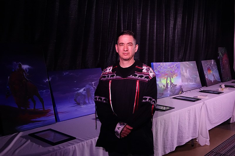 Jasyn Lucas stands in front of the paintings he created for the Thompson Urban Aboriginal Strategy t