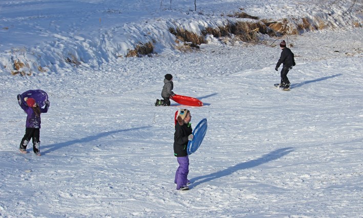 Mother Ashley Jeanes watches from above as daughter Aubree and a few other kids enjoy the slopes –Virden’s Scallion Creek ravine.