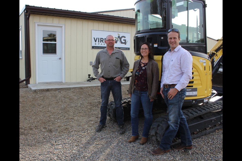 Virden Ag & Parts manager Guy Pounder and owners Genn and Matt Hipwell in front of their new business located five miles northeast of Virden at Wolverine Supplies. The machine, a mini-backhoe is part of a line of rentals offered.