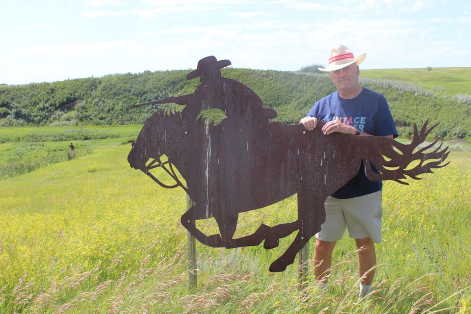 Kelvon Smith with one of the large metal cut-outs on the prairie near Batoche, silhouettes of Metis warriors, in their positions during the Battle of Fish Creek.