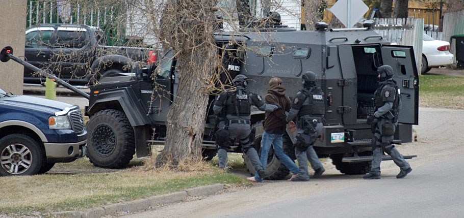 Light Armoured Vehicle, outfitted with a ram; MOCU make arrest. Subject appears to be barefoot.