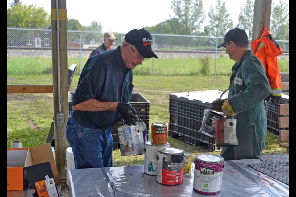 Virden Lions Club members Jim Tapp (l), Paul Pennycook (r) and Bryan Hayward (background) sort through discarded paint cans.