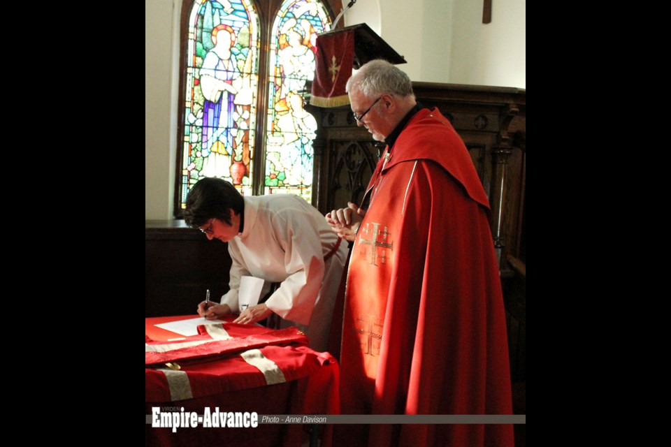 The Venerable Don Bernhardt, Priest of St. Mary’s Anglican Church in Virden, and Anna Sproul, as she signs a document at her ordination on June 29.