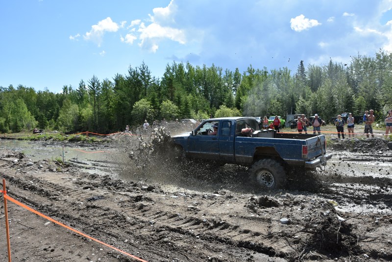 An older model GMC truck taking its run through Chell’s mud bog.