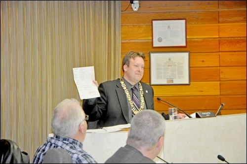 Mayor Ryan Bater holds up a copy of his SaskPower bill, which includes a line devoted to a five-per-cent charge for grants-in-lieu. Photos by John Cairns