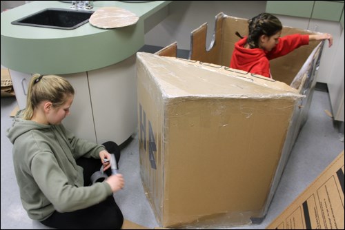 Lillian Knutson and Hailey Bjarnason tape up their boat project. - PHOTO BY ERIC WESTHAVER