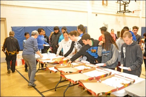 Students at Notre Dame school dive into the pizza provided after a presentation on money management. Photos by John Cairns
