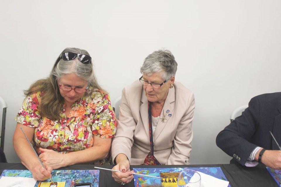Linda Murphy, left, and Shirley Andrist discuss the titles they created at the Estevan Art Gallery and Museum on Friday night.