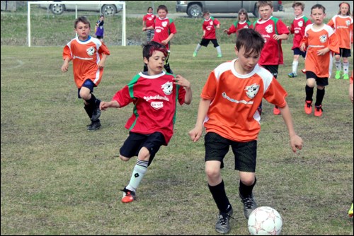 Greyson Laderoute of the Credit Union Crushers (from left) and Trey Andres of the Co-op Red Racers chase Rylan Raddysh while Noah Van Caeseele and Maddox Dominey look on during the team's May 23 Division 2 minor soccer matchup at Foster Park - PHOTO BY ERIC WESTHAVER