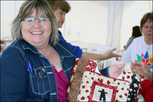 Lyla Yaremchuk displays a quilted pursue in one of the tents on the museum grounds.