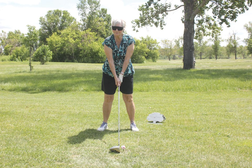 Madeline Skjerpen lines up her drive on the first hole while wearing a blindfold.
