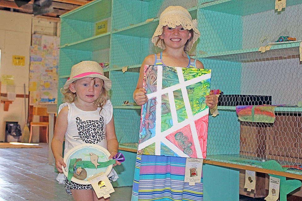 Mia, left, and Ava Poggemiller show off their entries to the Connaught Fair’s exhibits. The fair was held at the Silver Stream fairground July 29 and 20. Review Photo/Devan C. Tasa