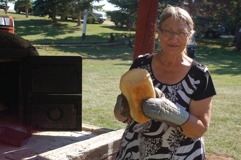 Greta German pulled out some freshly-baked bread from the outdoor clay oven.