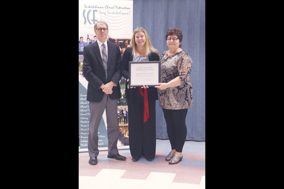 Dean Petersen, left, and Gayla Petersen, right, receive their award from Jennifer Lang, center.