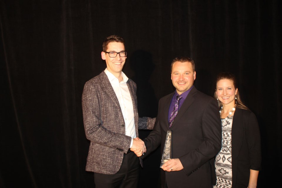 From left, Daryl Donovan from MNP presents the Business of the Year Award to Brent and Janelle Gedak.