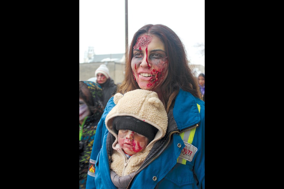 Logan Church and her son Dominyk staggered down Main Street during the Flin Flon Pride Zombie Walk on Oct. 28. Around 50 people braved subzero temperatures to partake in this year's event. - PHOTO BY ERIC WESTHAVER