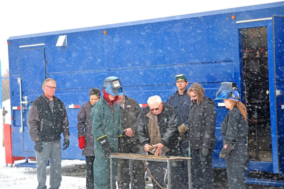 Board member Ron Kowalchuk cuts the metal bar in place of a ribbon.