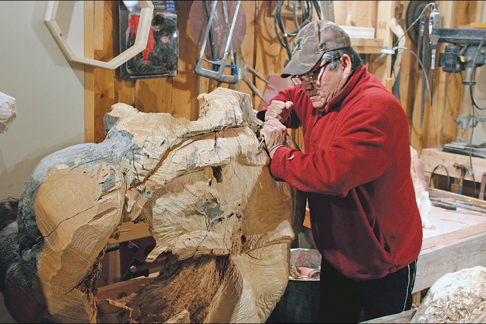 Carver and artist Irvin Head works on his latest piece, a face carved out of a large burl of wood. Head owns and operates his own gallery in Cranberry Portage and has been carving pieces in stone, wood, shells and other media for almost 20 years. - PHOTO BY ERIC WESTHAVER