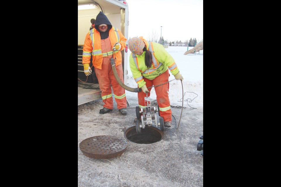 Rob Linderatsky and Amanda Medvid lower the city’s robot into the storm sewer at Delaere and Mayhew. Right, strange things can wash into the storm sewer system during nasty weather, such as this big rock.