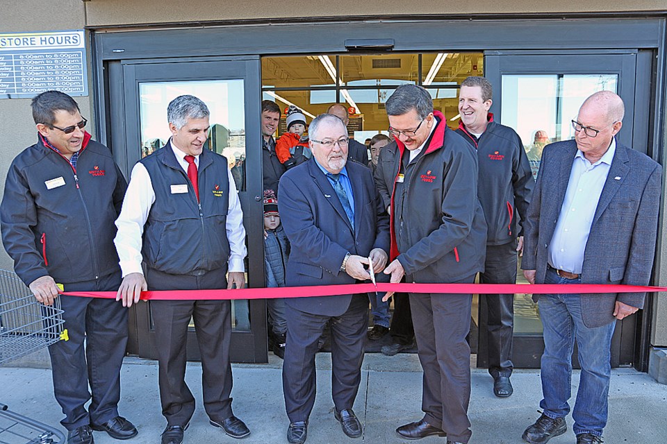 Al Jellicoe, Tisdale's mayor, and Dan Bregg, the president of Buy-Low Foods, both in the centre, cut the ribbon at the grand opening of Buy-Low's new Tisdale location. The others are, from left, Buy-Low employees Trevor Digeso, Sam Corea and Dereck Hein, and Carrot River Valley MLA Fred Bradshaw. Review Photo/Devan C. Tasa