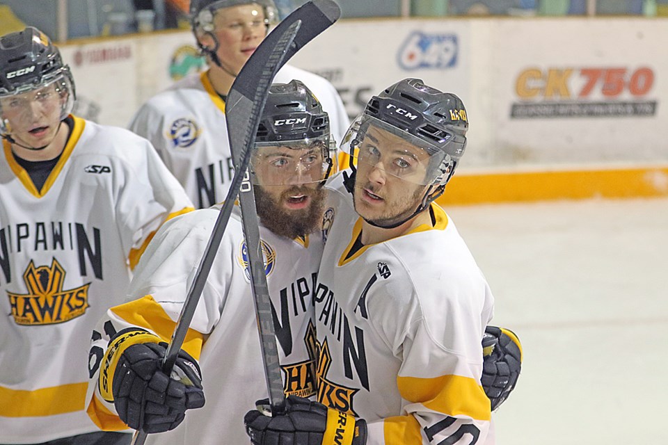 Thomas Lenchyshyn, right, congratulates Michael Grant, centre, on the ice after Grant scored the team's third goal during the game against the Flin Flon Bombers Dec. 5. Review Photo/Devan C. Tasa